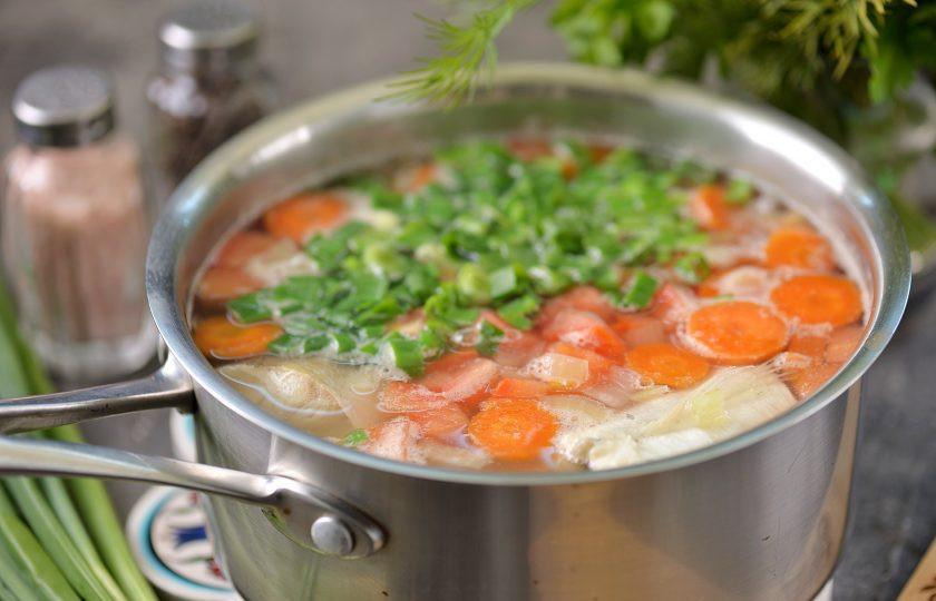 1. Этап. Уха из замороженной рыбы: Помидор нарежьте мелким кубиком, порубите зеленый лук, переложите их в суп, варите минут 5.