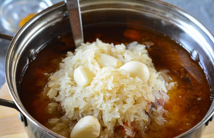 1. Этап. Плов с томатной пастой: Всыпьте хорошо промытый рис, добавьте зубчики чеснока, разровняйте крупу и прикройте плов крышкой. Томите на тихом огне 30 минут, пока рис не станет мягким.