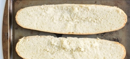 1. Этап. Пицца на батоне в духовке: 1. Первым делом включите духовку и пусть греется до 200 градусов. Подготовьте противень, можно смазать его чуточку маслом или застелить пергаментом. Разрежьте батон пополам и выложите на противень.