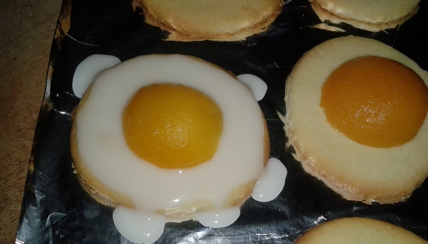 1. Этап. Печенье Пасхальные яйца: 7. На центр печенья выложите половинку абрикоса срезом вниз. Используя ложечку, смажьте все оставшееся пространство печенька глазурью.