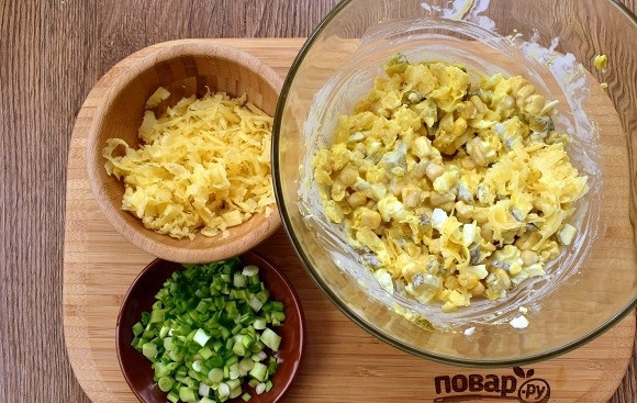 1. Этап. Вкуснейший салат Cказочная поляна: В миске соедините половину тертого сыра, кукурузу, огурец и яйца, перемешайте.