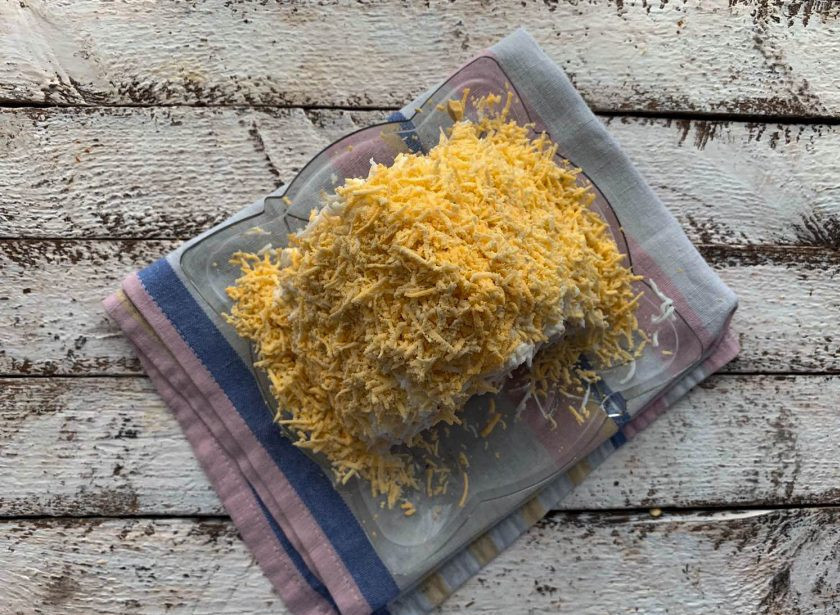 1. Этап. Салат Избушка из крабовых палочек: Очистите яйца от скорлупы и разделите на белок и желток. Сначала выложите тертый яичный белок, затем желток. Именно для того, чтобы тертый белок хорошо держался на «крыше», салат необходимо слегка промазать сверху майонезом.