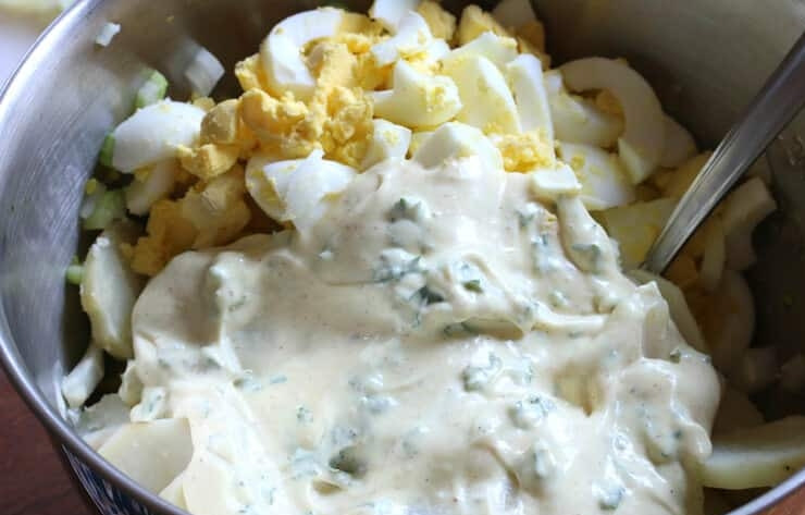1. Этап. Классический картофельный салат: 4. Отварите яйца вкрутую, нарежьте их небольшими кусочками. Выложите в миску к овощам яйца и картофель, добавьте заправку.
