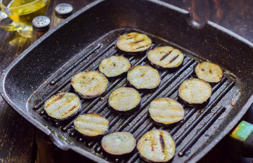 1. Этап. Хрустящие баклажаны с помидорами и кинзой: Сковороду прогрейте и смажьте маслом, выложите баклажаны и поджарьте их несколько минут с каждой стороны, до румяности.
