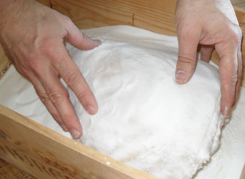 1. Этап. Пармская ветчина в домашних условиях: Соль выкладываем на дно ящика, хорошенько обсыпаем ею окорок. Потом полностью его засыпаем.