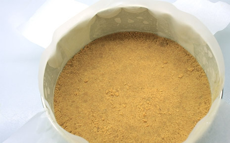 1. Этап. Чизкейк из печенья: Дно формы выкладываем пергаментом и утрамбовываем крошку, формируя невысокие бортики.