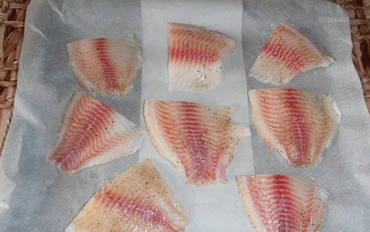 1. Этап. Тилапия в духовке с сыром: Застелите противень бумагой для выпечки. Выложите на него рыбу.