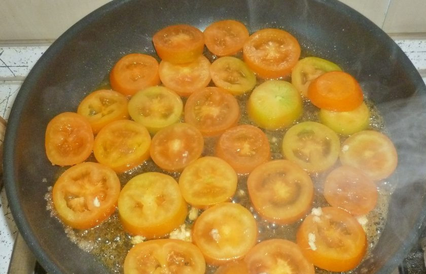 1. Этап. Тарт-татен с помидорами: Если используете замороженное тесто, предварительно его разморозьте. Духовку разогрейте до 200°. Помидоры нарежьте кружочками. В сковороде растопите масло и всыпьте сахар. Помешивайте, пока сахар не превратится в светлую карамель. Выложите помидоры, пропустите через пресс чеснок. Протушите овощи на слабом огне 2-3 минуты.