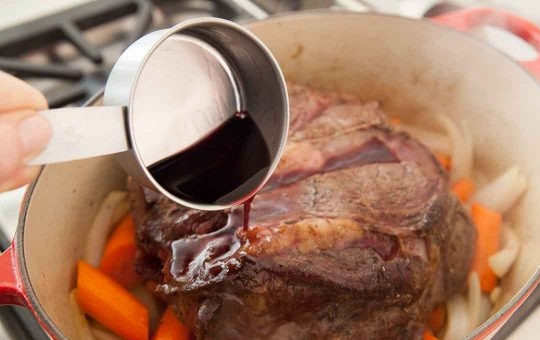 1. Этап. Говядина, тушеная в казане: 4. Выложите поверх овощей обжаренное мясо, добавьте вино и лавровый лист.