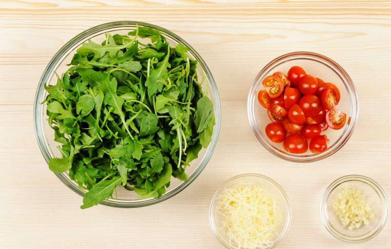 1. Этап. Салат Руккола с креветками: Рукколу промойте и обсушите, помидоры черри разрежьте пополам, пармезан натрите на терке, чеснок мелко порубите.