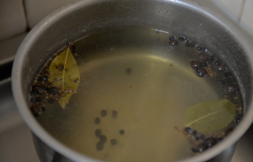 1. Этап. Рулетики из сельди в маринаде: Стакан воды вылейте в кастрюлю, доведите до кипения. Добавьте лавровый лист, белый лук, красный лук, перец горошком и бутоны гвоздики. Кипятите смесь, накрыв крышкой, на очень слабом огне в течение пятнадцати минут. После чего добавьте белое вино и продолжайте кипятить еще пять минут.