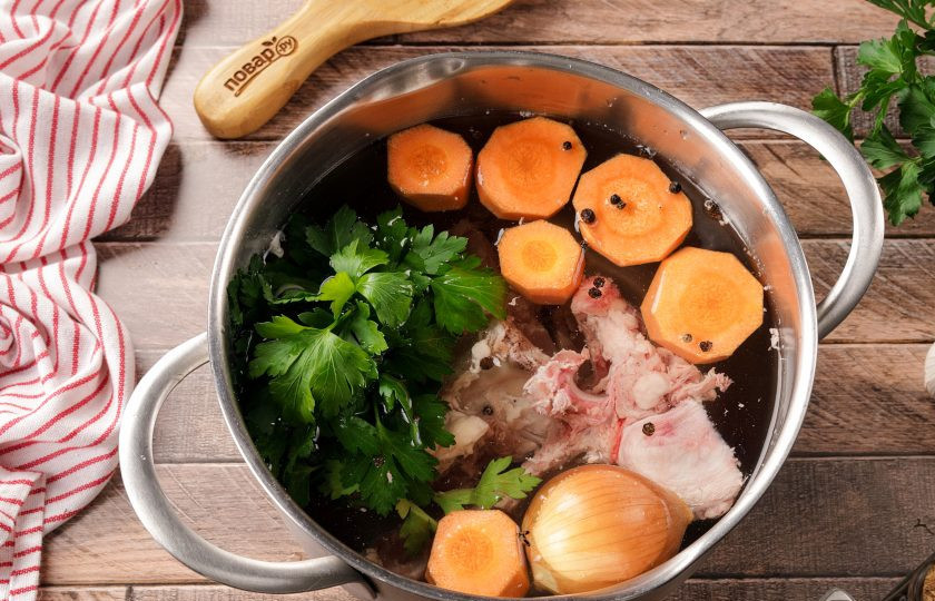 1. Этап. Кололик: Переложите кости в кастрюлю и залейте водой. Морковь очистите и разрежьте на несколько частей. У лука снимите верхнюю шелуху и хорошо промойте. Добавьте в кастрюлю подготовленные овощи, перец горошком и петрушку. Петрушку лучше завязать в пучок, чтобы проще было потом вытащить её из бульона. Поставьте кастрюлю на плиту и доведите до кипения. Снимите пену и варите на самом минимальном огне около 2 часов.