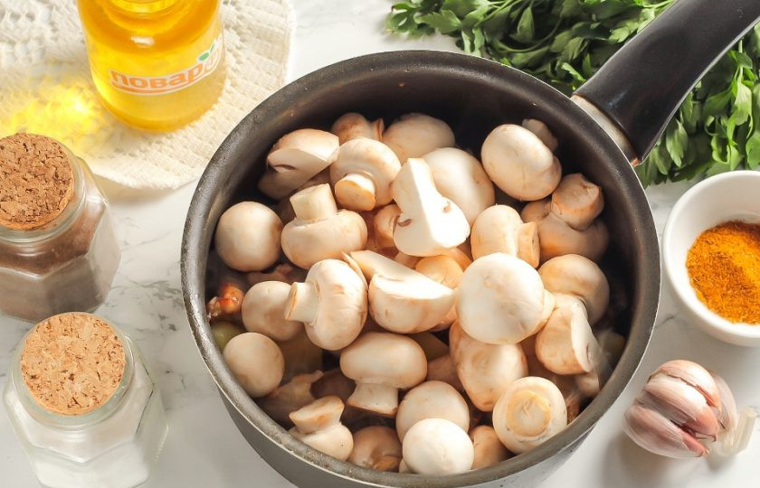 1. Этап. Баранина с картофелем и грибами: Нарежьте половину очищенного лука полукольцами и добавьте в емкость вместе с шампиньонами. Если грибы крупные, то нарежьте их на четвертинки. Обязательно посолите и перемешайте. Соль вытянет из грибов всю жидкость. Обжаривайте на умеренном нагреве примерно 8-10 минут. Грибы выпустят жидкость и все нарезки в ней пропарятся.