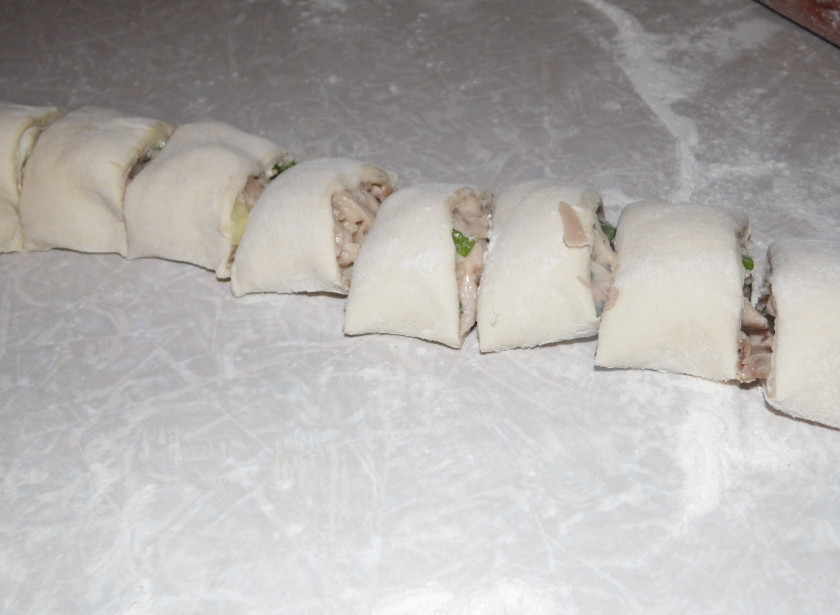 1. Этап. Быстрый киш с зеленым луком и курицей: Вторую часть теста также раскатываем в круг и выкладываем на одну его часть 1/3 начинки. Сворачиваем рулетом и нарезаем шайбочками толщиной в 2 см.