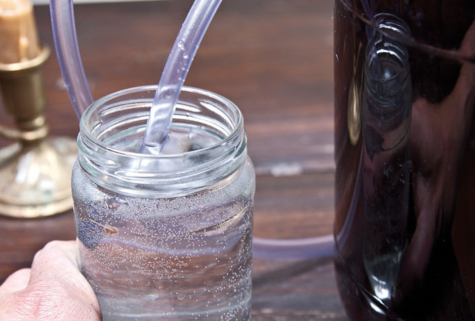 1. Этап. Вино из рябины: 8. Накройте банки крышками с гидрозатвором, опустив трубочку в емкость с водой. Оставьте примерно на 10-12 дней в темном и не очень теплом месте.