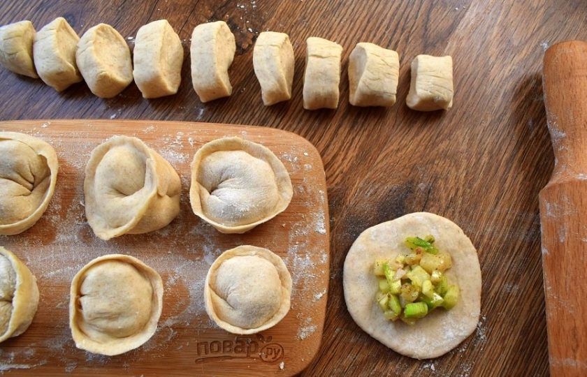 1. Этап. Вегетарианские пельмени с кабачками: Рабочую поверхность припылите мукой. Тесто разделите на 4 части, каждую скатайте в колбаску и разрежьте на равные кусочки. Раскатайте кусочек в круглую лепешку, в центр которой поместите 1 ч. л. начинки. Лепешку согните пополам, закрепите тщательно ее по краям и соедините концы вместе.