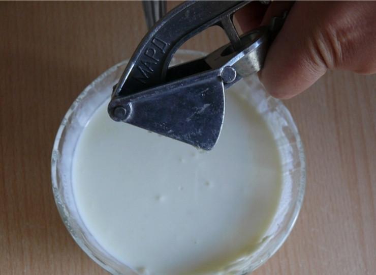 1. Этап. Котлеты с творогом: 5. Выдавливаем чеснок «чеснокодавкой» в сметану. Тщательно перемешиваем.