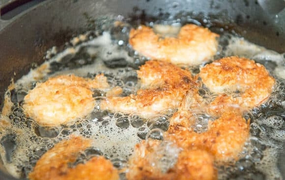 1. Этап. Креветки в кокосовой стружке: В глубокой сковороде разогрейте масло. Обжарьте в нём креветки с обеих сторон по 2 минуты.