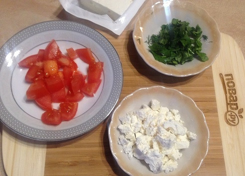 1. Этап. Салат с пастой, баклажанами и брынзой: 6. Помидор нарежем кубиками, мелко порубим зелень и раскрошим брынзу.