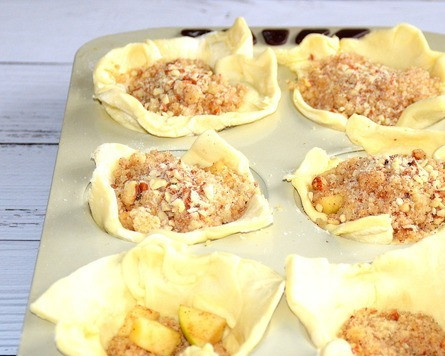 1. Этап. Слойки с яблоками и миндалем: Разложить в формочки со слоёным тестом сначала часть штрейзеля, затем слой яблок и сверху посыпать оставшимся штрейзелем.