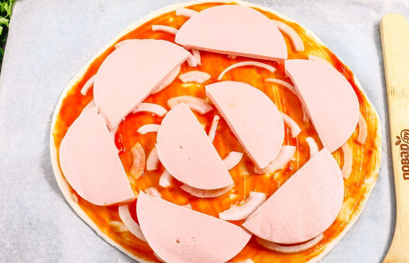 1. Этап. Пицца с колбасой из слоеного теста: Вареную колбасу нарежьте ломтиками и выложите на луковый слой.