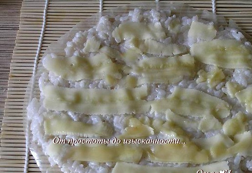 1. Этап. Десертные суши Кокос, банан и имбирь: Лист рисовой бумаги сбрызните водой (или окуните на пару секунд в воду), выложите 1/3 риса, равномерно распределите, сверху выложите банан, нарезанный тонкими пластинами, добавьте по вкусу лепестки имбиря.