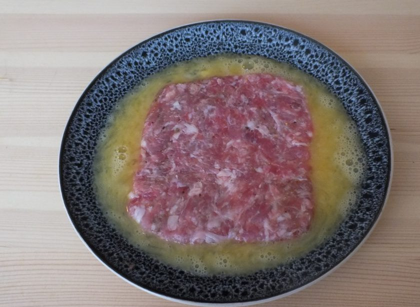 1. Этап. Лепешки из фарша: 4. Взбейте 1 яйцо и вылейте в плоскую тарелку. Переложите аккуратно в яичную массу мясную лепешку. Хорошо обмажьте со всех сторон.