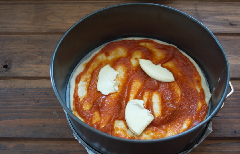 1. Этап. Пицца с шампиньонами, колбасой и сыром: Тесто смазать томатным соусом. Тонкими пластинками нарезать сливочное масло и выложить поверх томатного соуса.