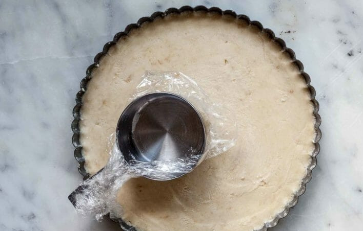 1. Этап. Песочное печенье с миндалем: 4. С помощью мерного стаканчика, завернутого в пищевую пленку, распределите тесто равномерным слоем по форме.