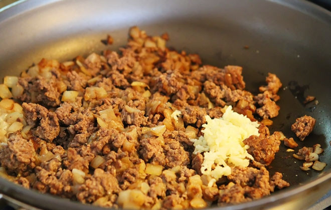 1. Этап. Быстрая лазанья на плите: 2. Обжарьте фарш с луком в течение нескольких минут, помешивая, на среднем огне. Добавьте пропущенный через пресс чеснок.