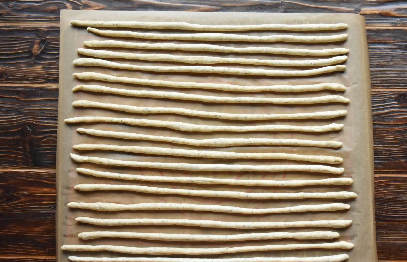 1. Этап. Гриссини на закваске: Каждый кусочек раскатайте в длиную соломку. Размер и толщину гриссини регулируйте по своему усмотрению. Выложите гриссини на противень, застеленный пергаментной бумагой.