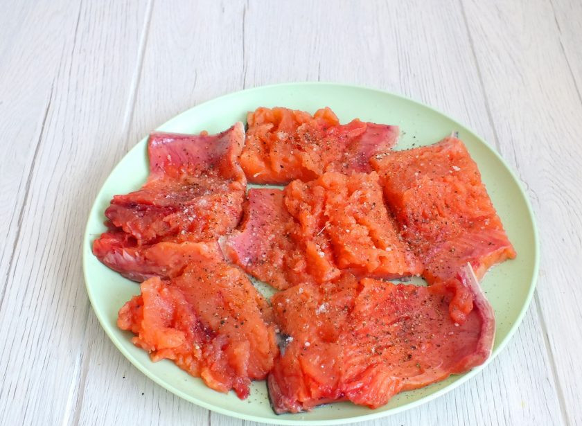 1. Этап. Горбуша с кабачком в духовке: Горбушу профилируйте, оставьте на коже. Удалите всевозможные мелкие косточки. Разрежьте на порционные кусочки. Разложите на блюдо. Посолите, приправьте перцем. Отставьте в сторону.