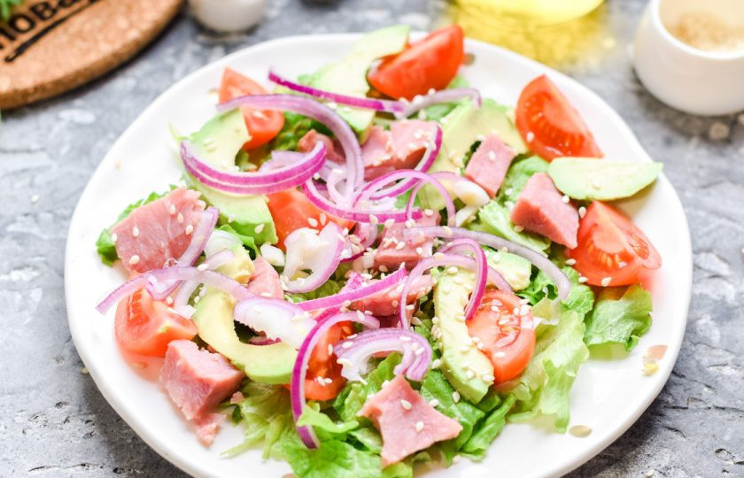 1. Этап. Салат из авокадо с ветчиной: Нарежьте лук полосками и добавьте ко всем ингредиентам. Следом посыпьте салат солью, перцем, кунжутом. Полейте салат маслом и подавайте к столу.