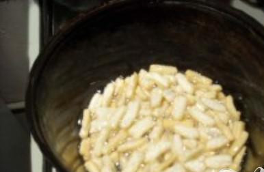 1. Этап. Чак-чак: 7. Нагреть масло в казане. Обжаривать лапшу в масле небольшими порциями. Периодически помешивать лапшу во время приготовления. Готовая лапша должна принять кремовый цвет.