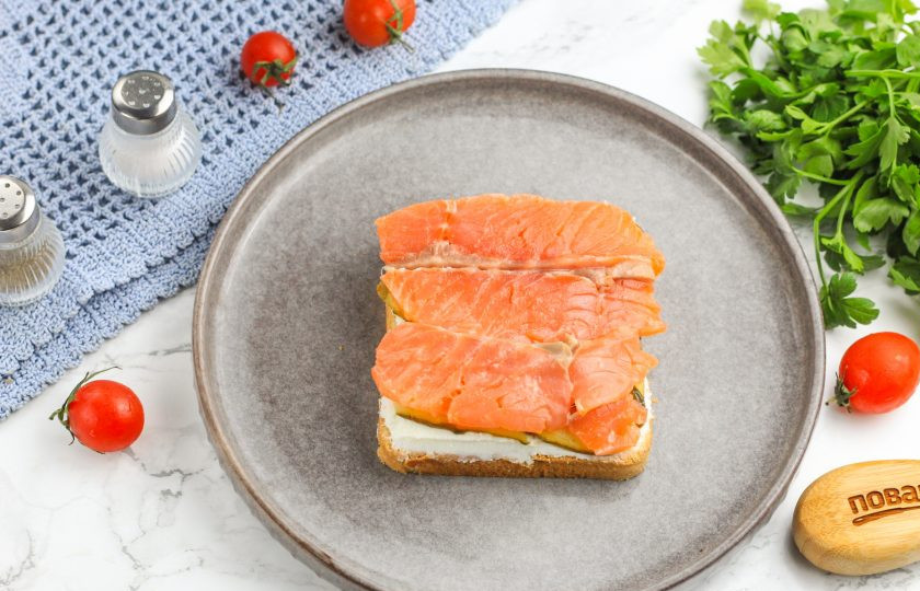 1. Этап. Канапе с семгой и икрой: Половину слабосоленой семги нарежьте ломтиками и выложите на ленты огурца.