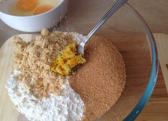 1. Этап. Цитрусовые кантуччи с фундуком: 2. Смешиваем просеянную муку с разрыхлителем, добавим сахар, миндальную муку и цедру. Размешаем и добавим одно целое яйцо и желток от второго. Замешиваем тесто.