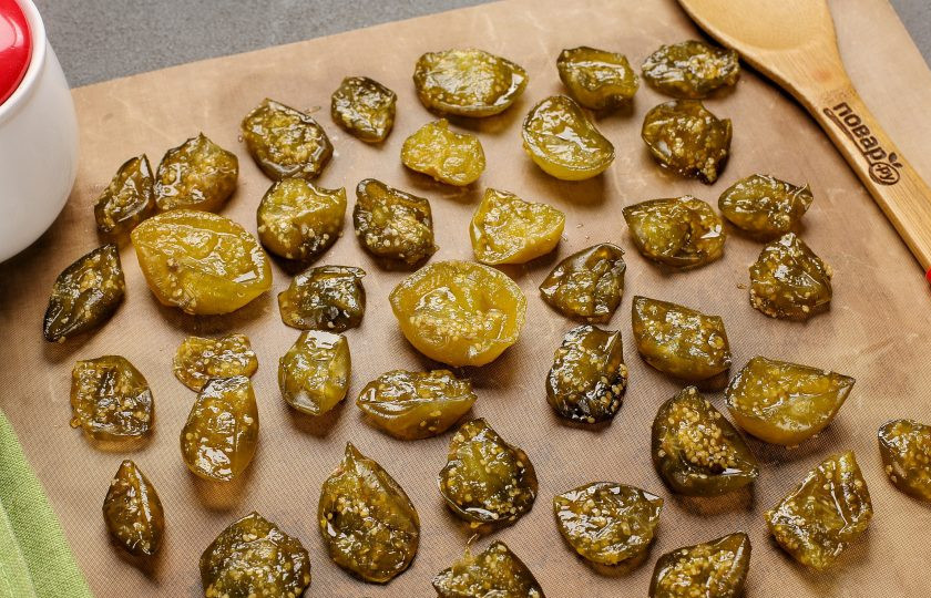 1. Этап. Цукаты из физалиса: Отобрав целые и красивые плоды, разложите их на противне. Сверху прикройте пергаментом и для того, чтобы получились цукаты, хорошо их просушите. Можно оставить физалис сохнуть при комнатной температуре, а можно высушить в духовом шкафу при температуре от 35 до 40 градусов или в электросушилке. Маленький совет: если будете сушить естественным образом или в духовке, то лучше выложить физалис на силиконовый коврик и тогда у вас не возникнет сложностей с отставанием сладких цукатов от поверхности, к которой они могут местами довольно крепко пристать.