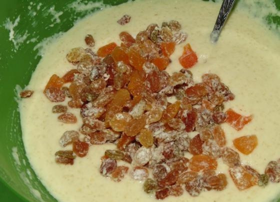 1. Этап. Манник с сухофруктами: Соедините масло, яйца с сахаром и манную крупу с кефиром в одной ёмкости. Туда же отправьте нарезанную курагу и изюм. Постепенно в тесто введите стакан муки. Всё хорошо перемешайте.