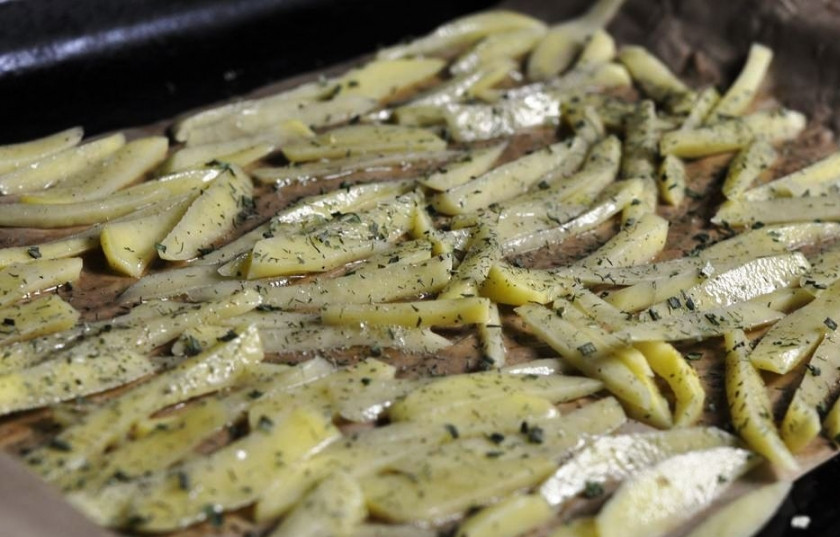 1. Этап. Диетическая картошка в духовке: Обмакните картофель в яйцо и разложите на противне, застеленном пергаментом. Посыпьте зеленью.