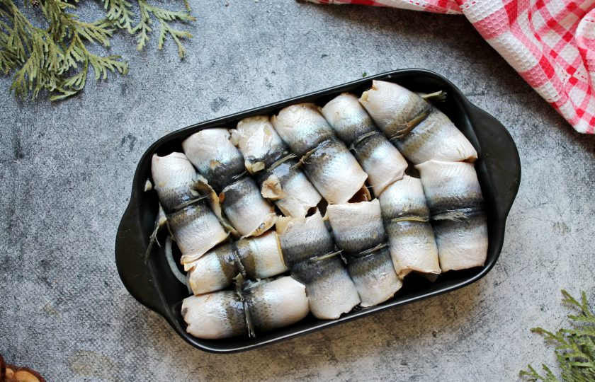 1. Этап. Салака в томате: Выложите плотно все рулетики из салаки в форму на репчатый лук.