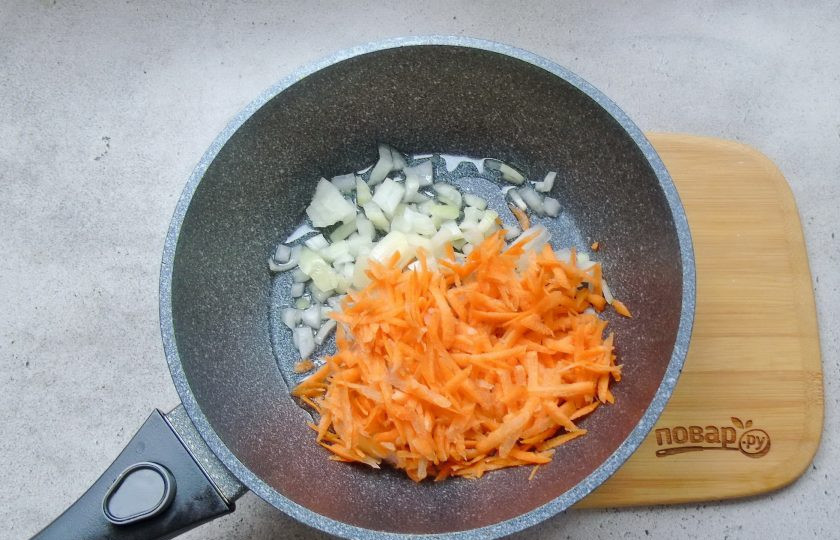 1. Этап. Окорочка с рисом в духовке: Тем временем лук мелко нарежьте, а морковь натрите на терке. Выложите в сковороду с подсолнечным маслом.