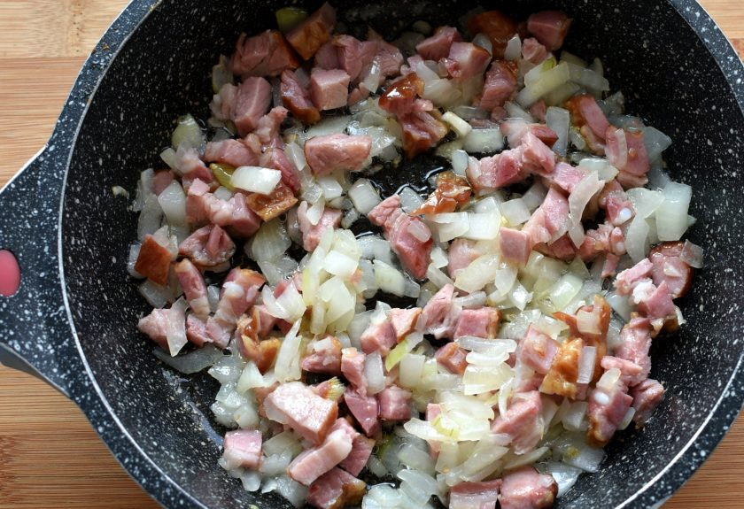 1. Этап. Зразы Беловежские: Для начинки мелко нашинкуйте лук и прогрейте его на топленом масле до прозрачности. Добавьте кубики ветчины и немного обжарьте.