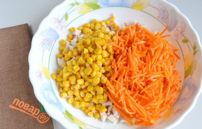 1. Этап. Салат на Новый год 2025: 3. С кукурузы слейте жидкость, положите в салат, добавьте морковь.
