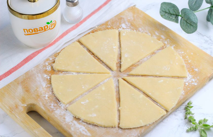 1. Этап. Рогалики песочные с орехами: Охлажденное тесто разделите на равные части и раскатайте каждую в округлый пласт, подпылив рабочую поверхность или доску мукой. Разрежьте круг на восемь треугольников.