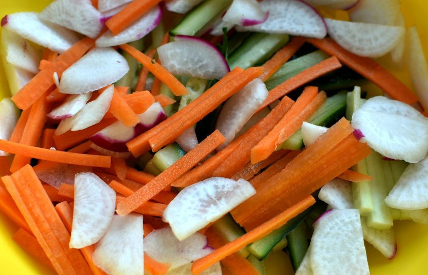 1. Этап. Хрустящий салат с курицей и овощами: Овощи очистите, промойте и обсушите. Нарежьте вручную соломкой огурцы и морковь, тонкими кружочками – редис. Выложите в глубокую миску, слегка присолите и посыпьте черным перцем.