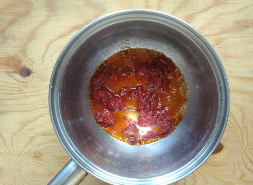 1. Этап. Сосиски под соусом с макаронами: 5. Затем добавьте сливочное масло и томатную пасту. Помешивая, обжарьте продукты 30 секунд.