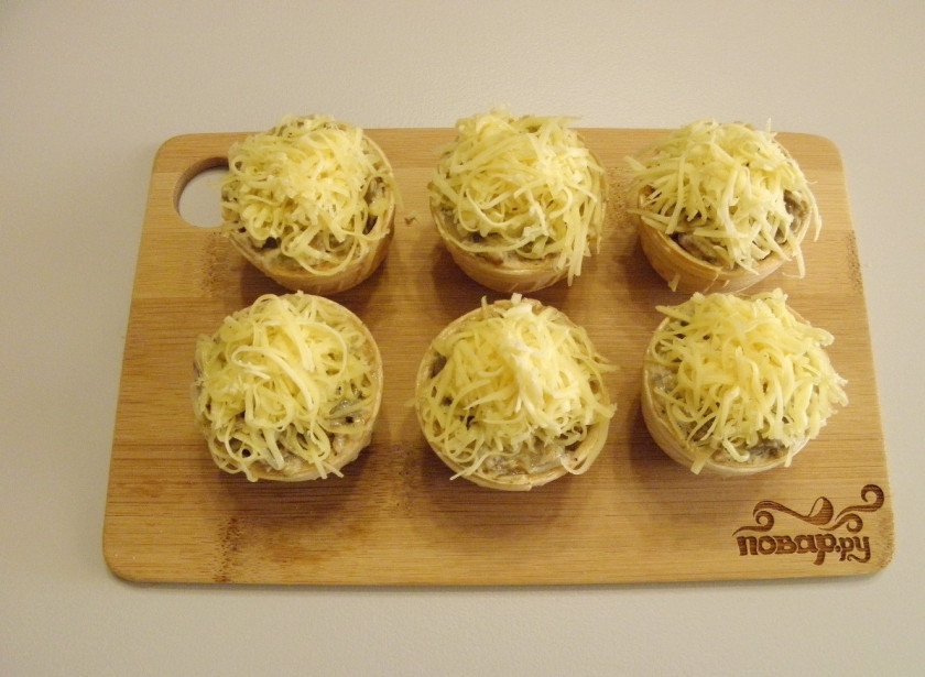 1. Этап. Жульен в тарталетках: Щедро посыпьте сыром тарталетки, я бы даже сказала — уложите сыр горкой. Отправьте тарталетки на 10 минут в горячую духовку (180-190 градусов), чтобы сыр расплавился.