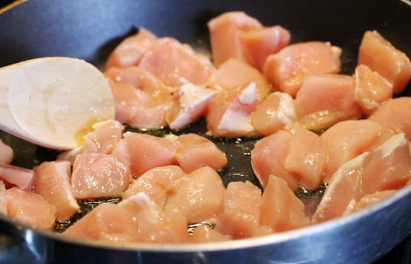 1. Этап. Курица по-японски: Пока варится рис, готовим курицу. Нарежьте её небольшими кусочками, выложите их на разогретую сковороду, политую оливковым маслом.