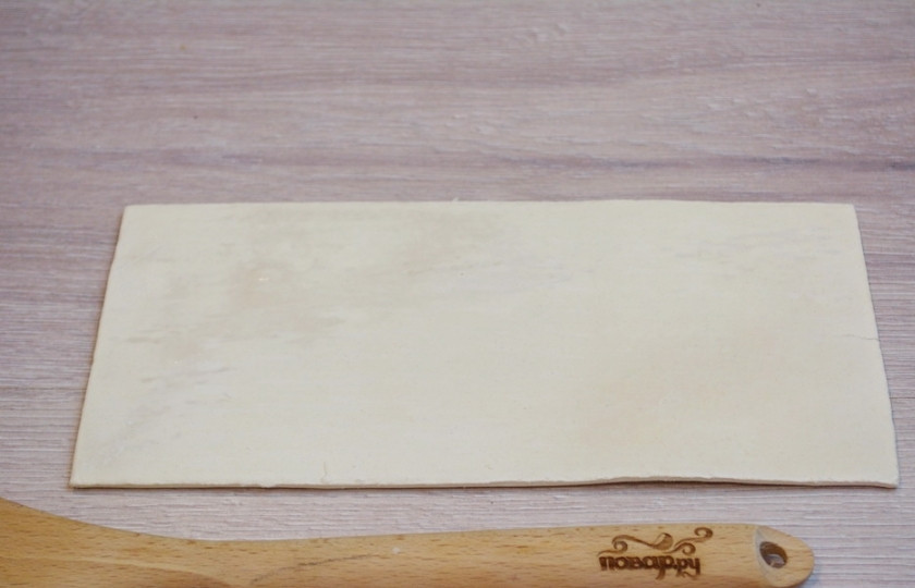 1. Этап. Конвертики из слоеного бездрожжевого теста: Для приготовления конвертиков из слоеного бездрожжевого теста нам надо взять само тесто. Разморозьте его. Стол присыпьте мукой, раскатайте тесто в пласт толщиной 0,5 см.
