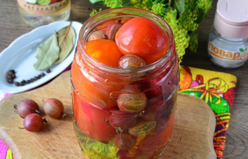 1. Этап. Помидоры с крыжовником на зиму: Заполните банки помидорами и крыжовником, залейте овощи кипятком и оставьте на 10 минут.